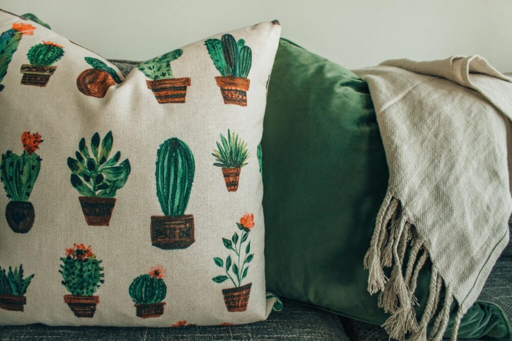 A cozy modern interior featuring cactus print throw pillows and a soft blanket on a sofa.